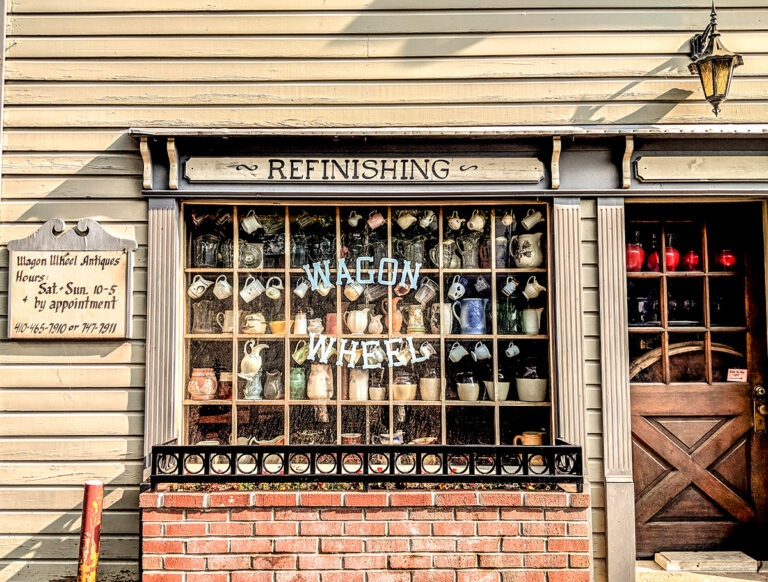 Rustic architectural photography of an antique shop exterior, highlighting textured brickwork, weathered wood, and a window display of vintage ceramics by Visuals for Vigil.